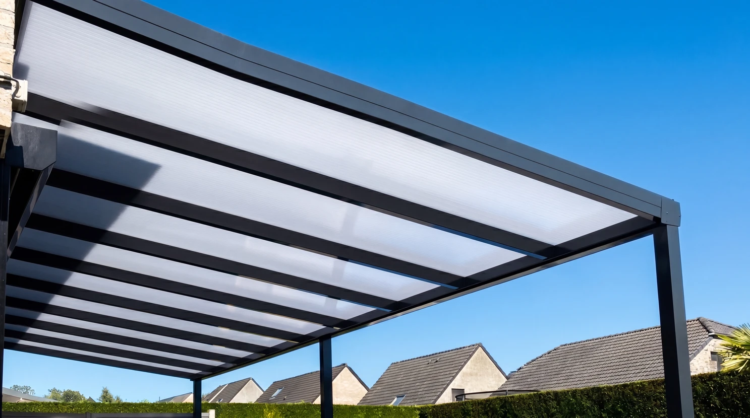 Pergola bioclimatique en aluminium anthracite avec toiture en polycarbonate alvéolaire translucide, montée sur poteaux carrés